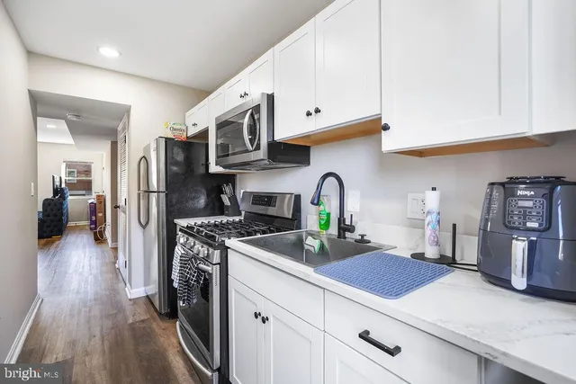 a kitchen with stainless steel appliances granite countertop a refrigerator a stove and a sink with cabinets