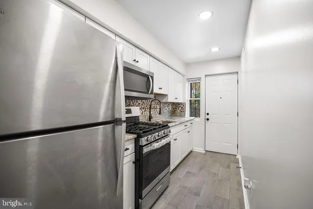 a kitchen with a refrigerator a stove top oven and cabinets