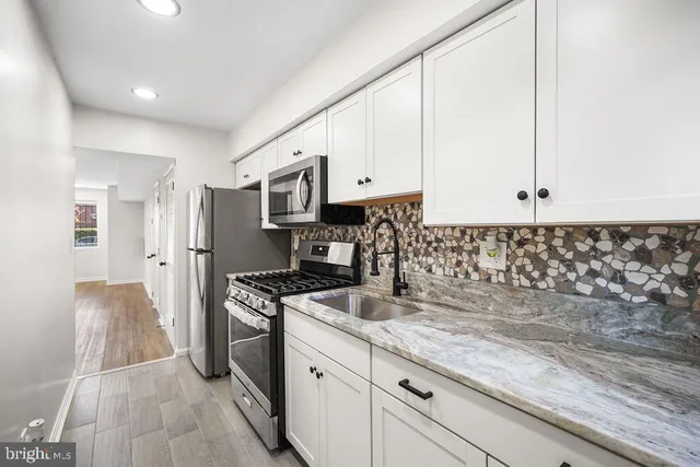 a kitchen with granite countertop white cabinets and stainless steel appliances