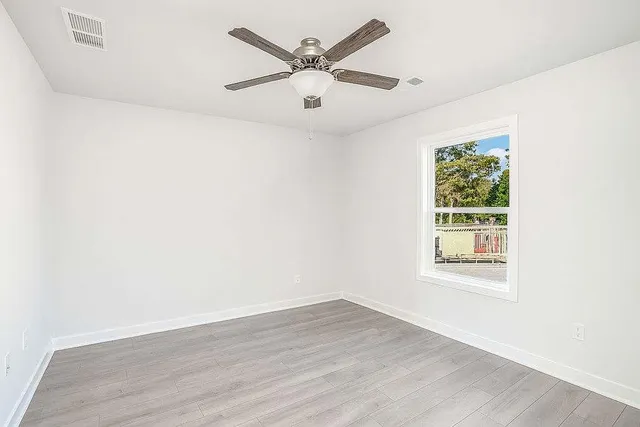 an empty room with wooden floor and windows