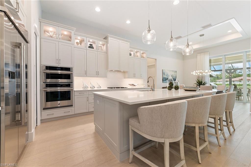 8916 Nevis Way Naples, FL 34112 - Photo 13 of 50 a kitchen with kitchen island cabinets and chairs