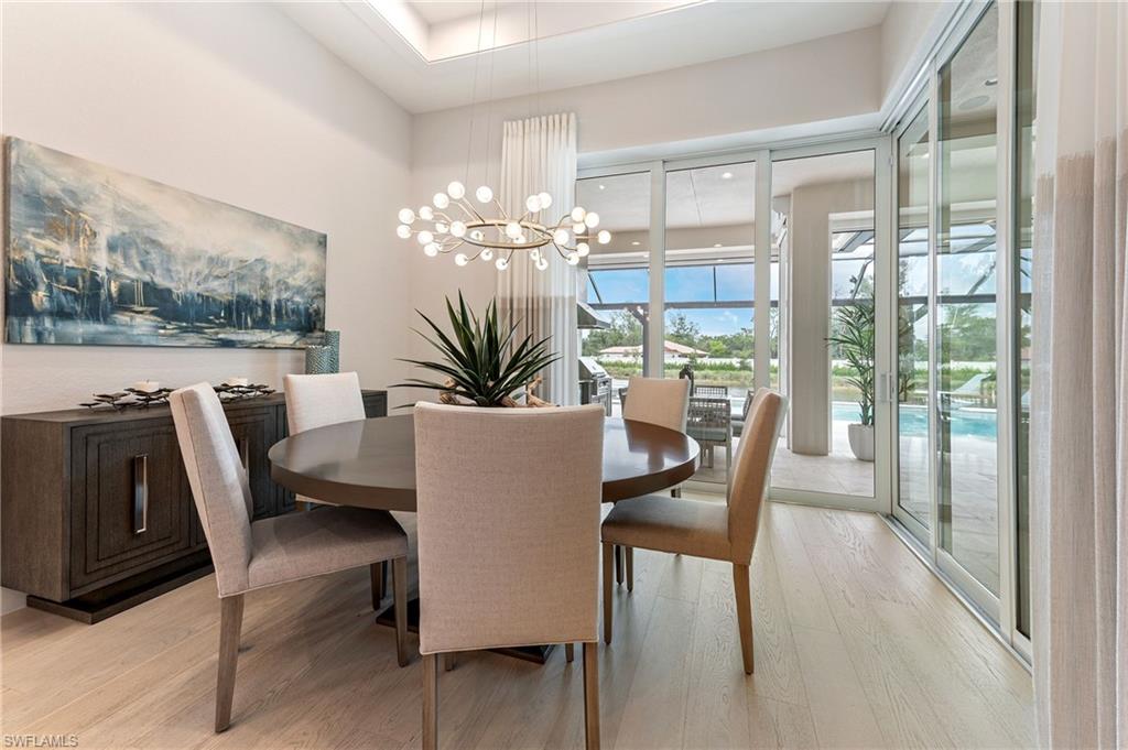 8916 Nevis Way Naples, FL 34112 - Photo 9 of 50 a dining room with furniture a floor to ceiling window and a kitchen view