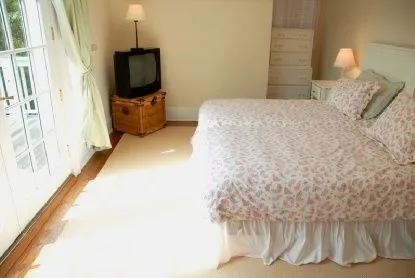 a bedroom with a bed and a flat tv screen on dresser