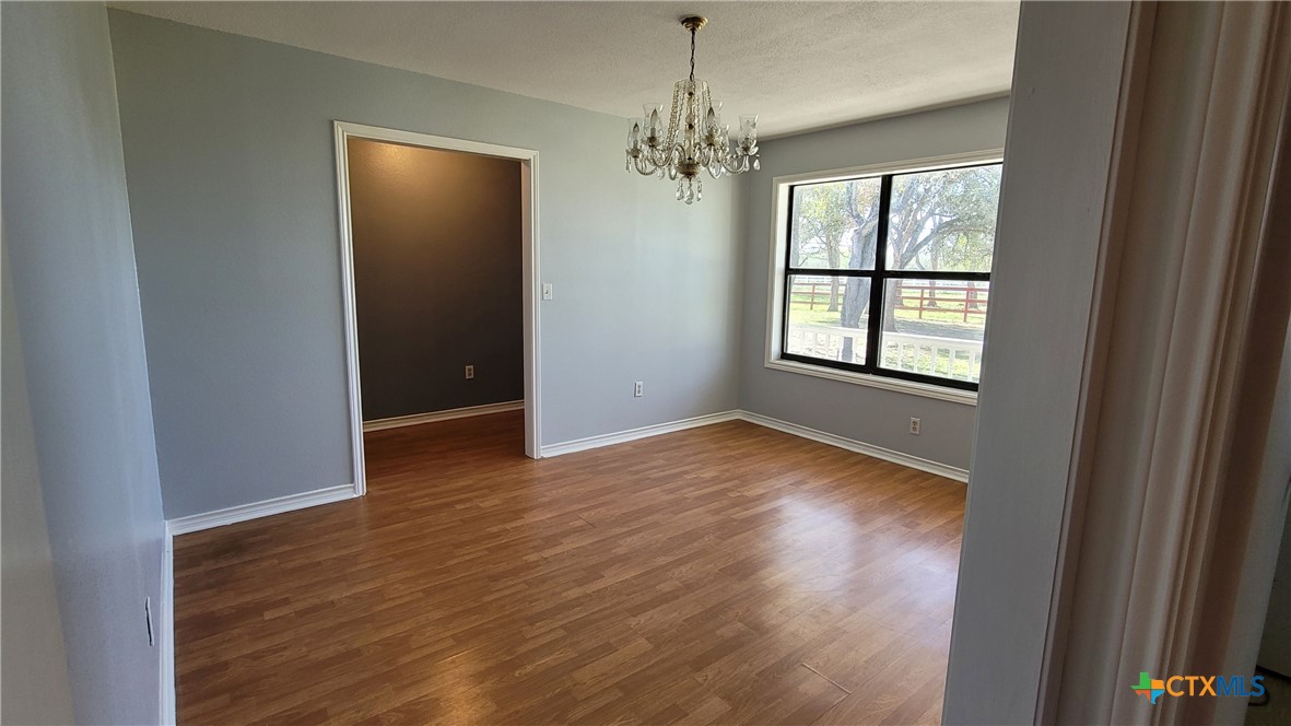 127-129 McAdams Road Goliad, TX 77963 - Photo 8 of 33 an empty room with wooden floor chandelier and windows