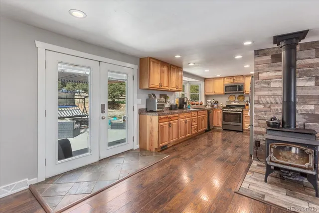 a kitchen with stainless steel appliances kitchen island granite countertop a stove top oven a sink dishwasher a dining table and chairs with wooden floor