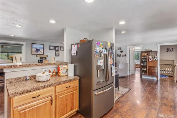 a kitchen with granite countertop a refrigerator and wooden floor