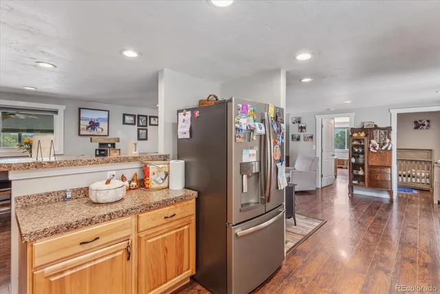 a kitchen with granite countertop a refrigerator and wooden floor
