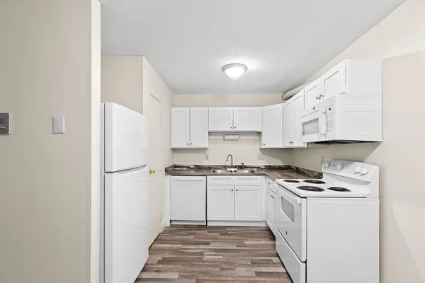 a kitchen with white cabinets and white appliances