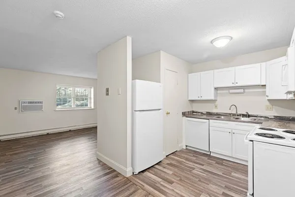 a kitchen with granite countertop white cabinets and white appliances