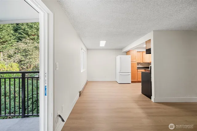 a view of a hallway with wooden floor and a kitchen