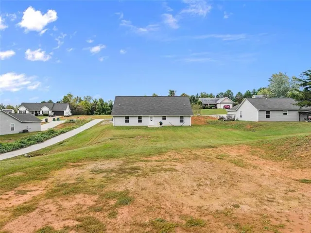 a view of a house with a yard and a large tree