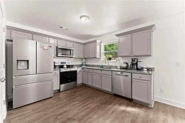 a kitchen with stainless steel appliances a refrigerator sink and white cabinets