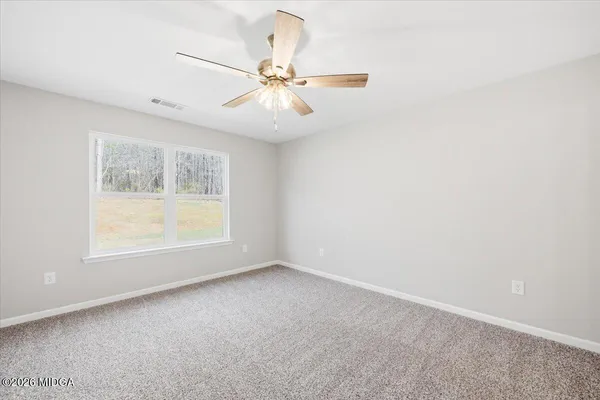 an empty room with windows and fan
