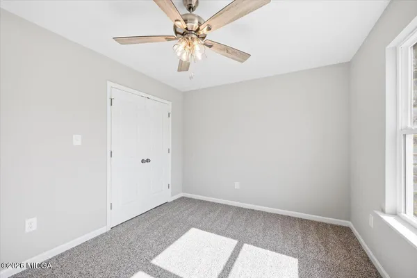 an empty room with windows and fan