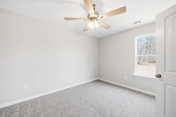 an empty room with windows and fan
