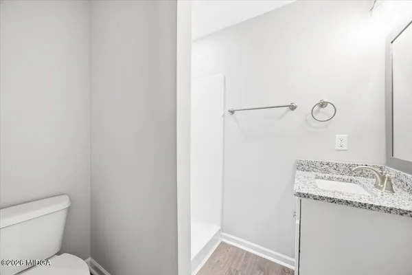 a bathroom with a granite countertop sink a toilet and a mirror