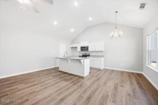 a view of kitchen with refrigerator microwave and stove with wooden floor