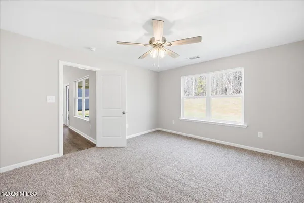 an empty room with chandelier fan and windows