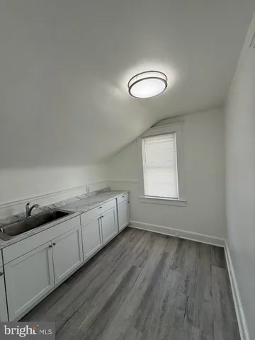 a view of a kitchen with wooden floor and white cabinets