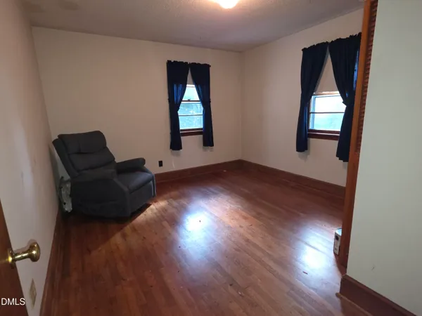 an empty room with wooden floor a ceiling fan and windows