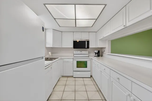 a kitchen with a sink a stove top oven and white cabinets