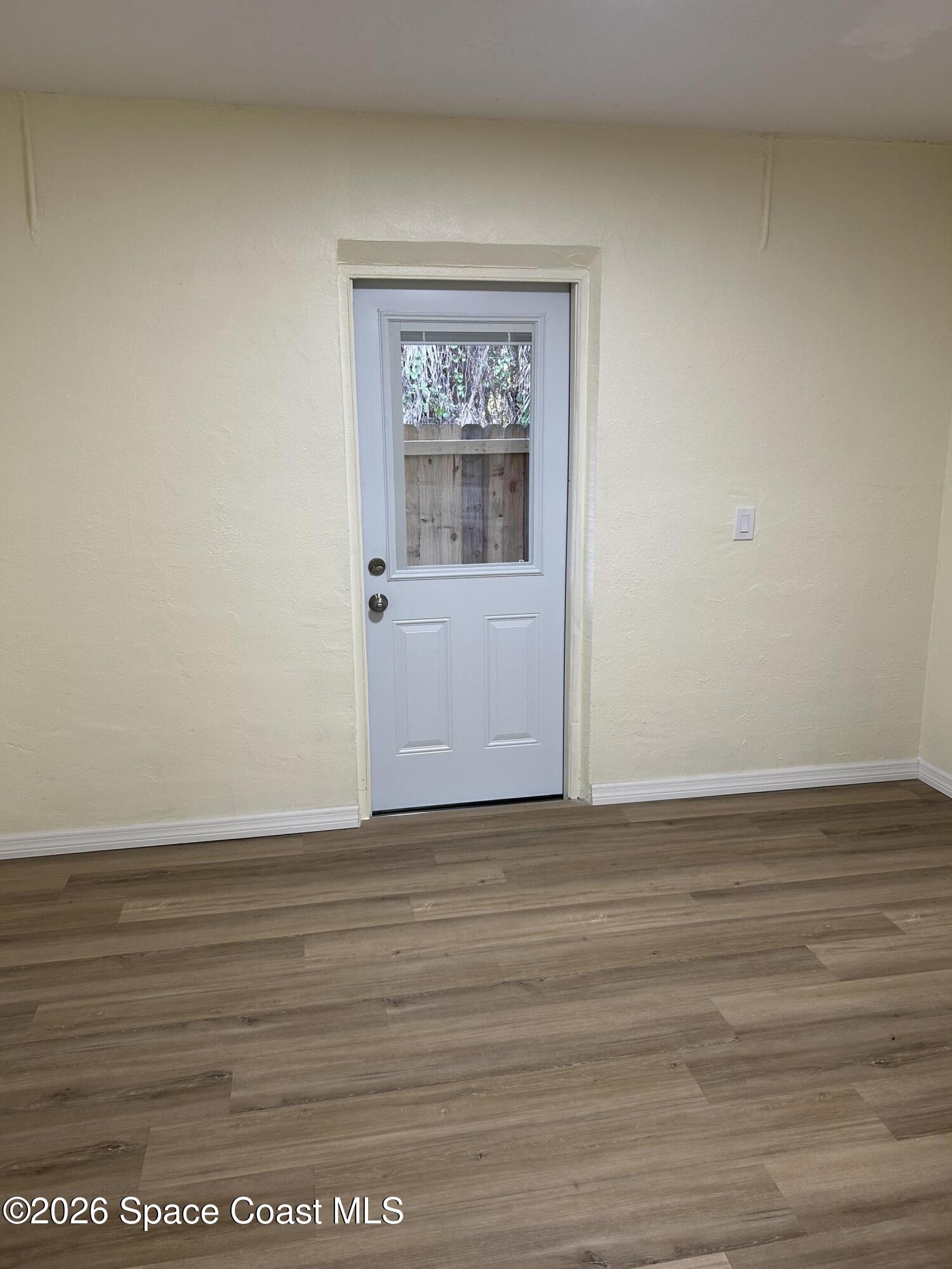3785 Bird Street Cocoa, FL 32927 - Photo 3 of 15 a view of an empty room with wooden floor and a window