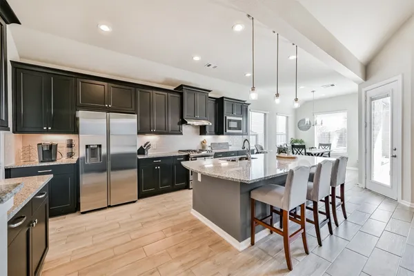 a large kitchen with stainless steel appliances kitchen island granite countertop a large island in the center