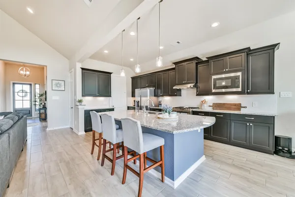 a kitchen with stainless steel appliances granite countertop a stove top oven a sink dishwasher a dining table and chairs with wooden floor