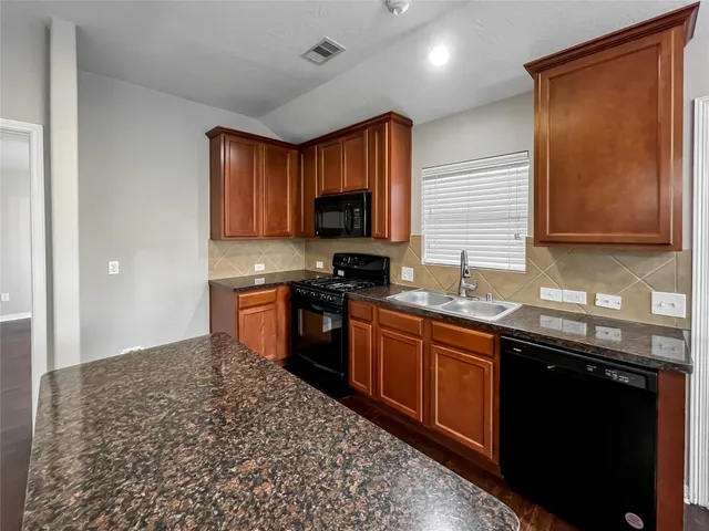 a kitchen with stainless steel appliances granite countertop a stove a sink and a microwave