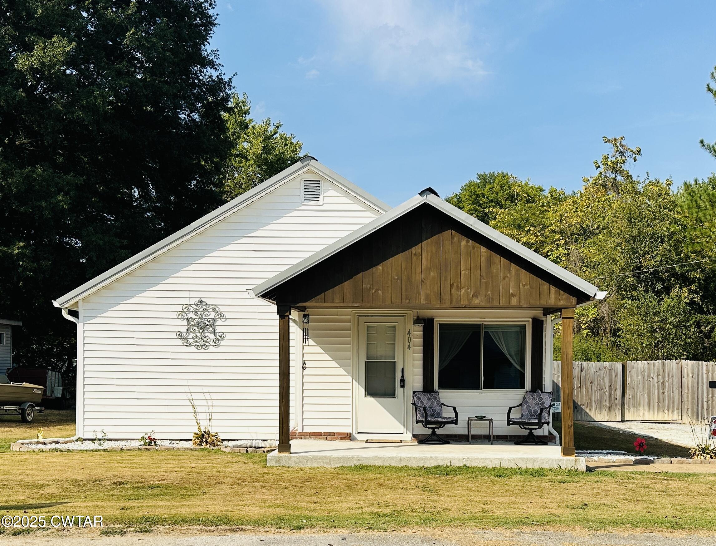a view of a house with a yard outdoor seating and covered with trees in the background