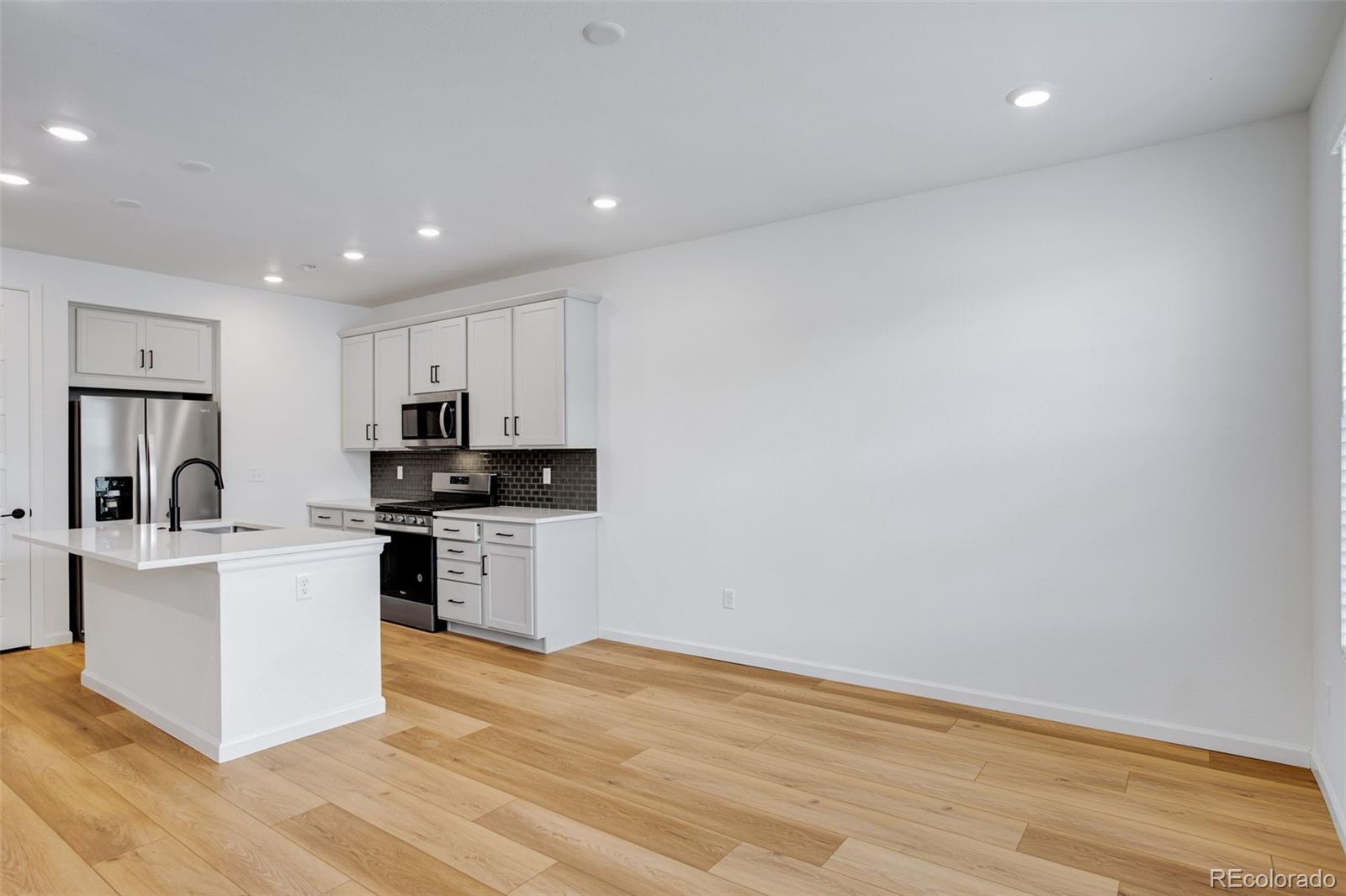 1765 Mount Meeker Avenue Berthoud, CO 80513 - Photo 14 of 37 a kitchen with white cabinets and stainless steel appliances