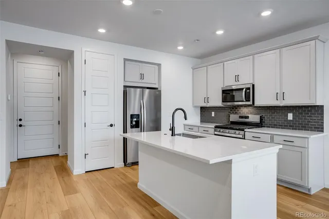 a kitchen with stainless steel appliances granite countertop a stove a sink and a microwave