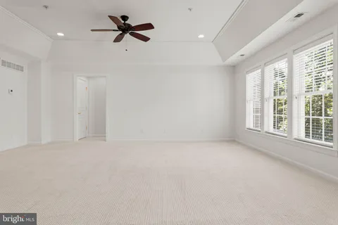 an empty room with windows and chandelier fan