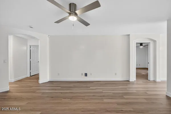 an empty room with wooden floor and ceiling fan