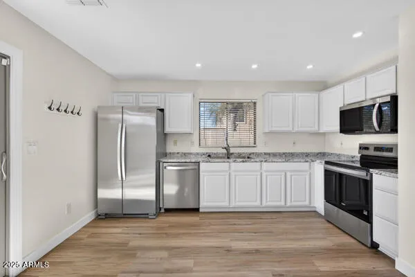 a kitchen with granite countertop a refrigerator and a stove top oven