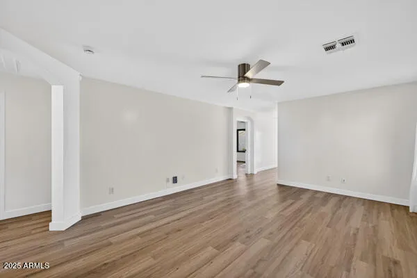 an empty room with wooden floor and ceiling fan
