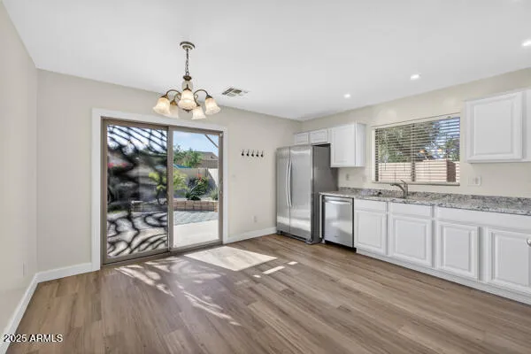 a kitchen with granite countertop a stove a sink a refrigerator and a wooden floor