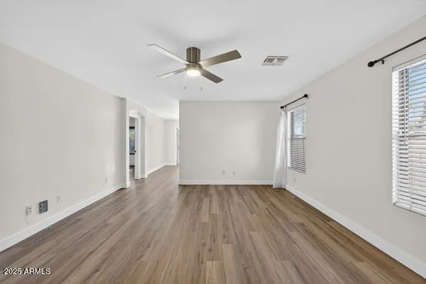 a view of empty room with wooden floor and fan