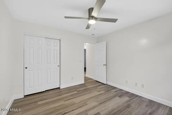 an empty room with wooden floor ceiling fan and windows
