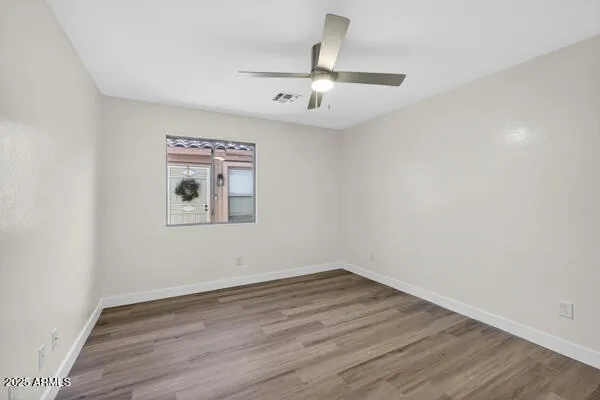 an empty room with wooden floor ceiling fan and window