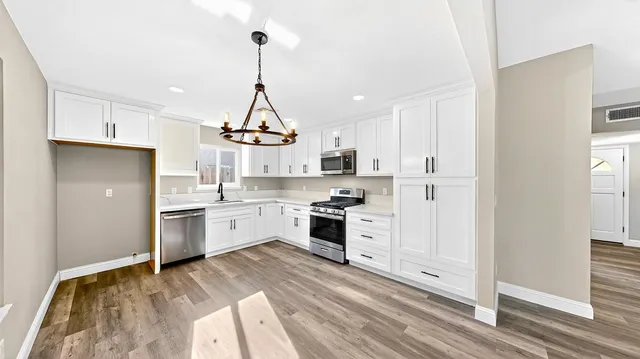 a kitchen with granite countertop white cabinets and stainless steel appliances
