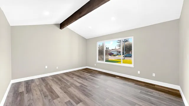 a view of an empty room with window and wooden floor