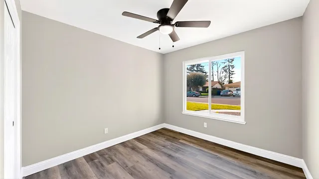 an empty room with a window and a ceiling fan
