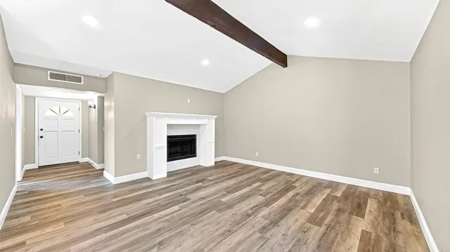 a view of empty room with wooden floor and fireplace