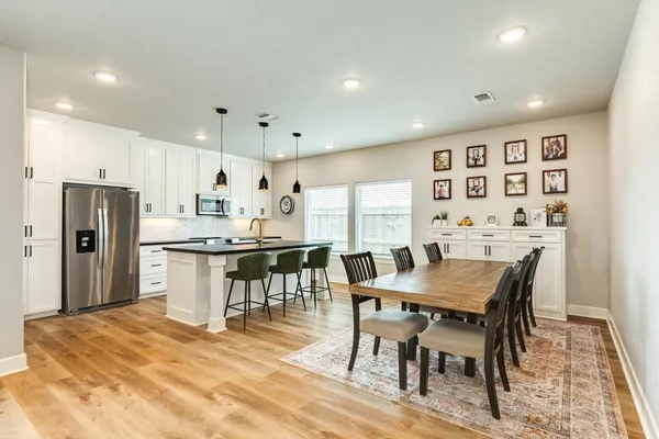 a kitchen with stainless steel appliances granite countertop a kitchen island a stove a table and a refrigerator
