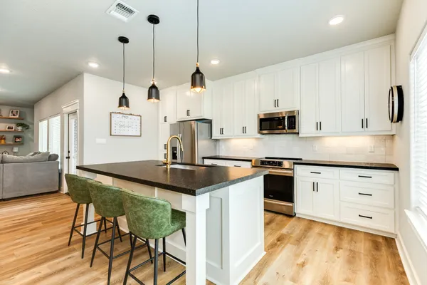 a kitchen with stainless steel appliances granite countertop a sink a stove a refrigerator and island with wooden floor