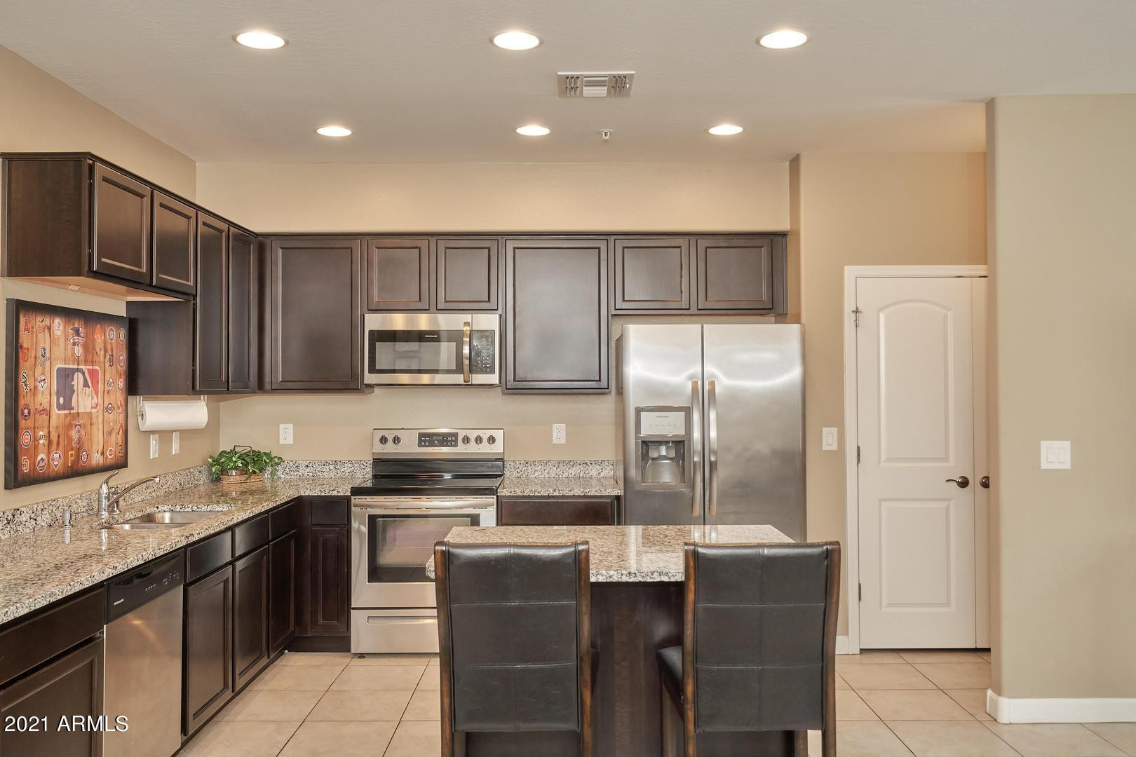 240 West Juniper Avenue, Unit 1089 Gilbert, AZ 85233 - Photo 4 of 24 a kitchen with stainless steel appliances granite countertop a refrigerator a sink a stove a dining table and chairs