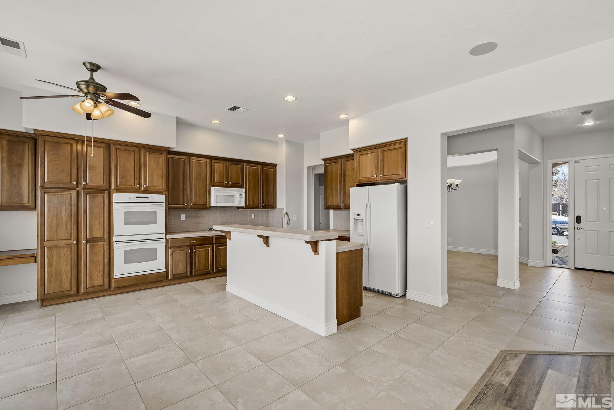 8115 Fire Opal Lane Reno, NV 89506 - Photo 12 of 40 a large white kitchen with cabinets and stainless steel appliances