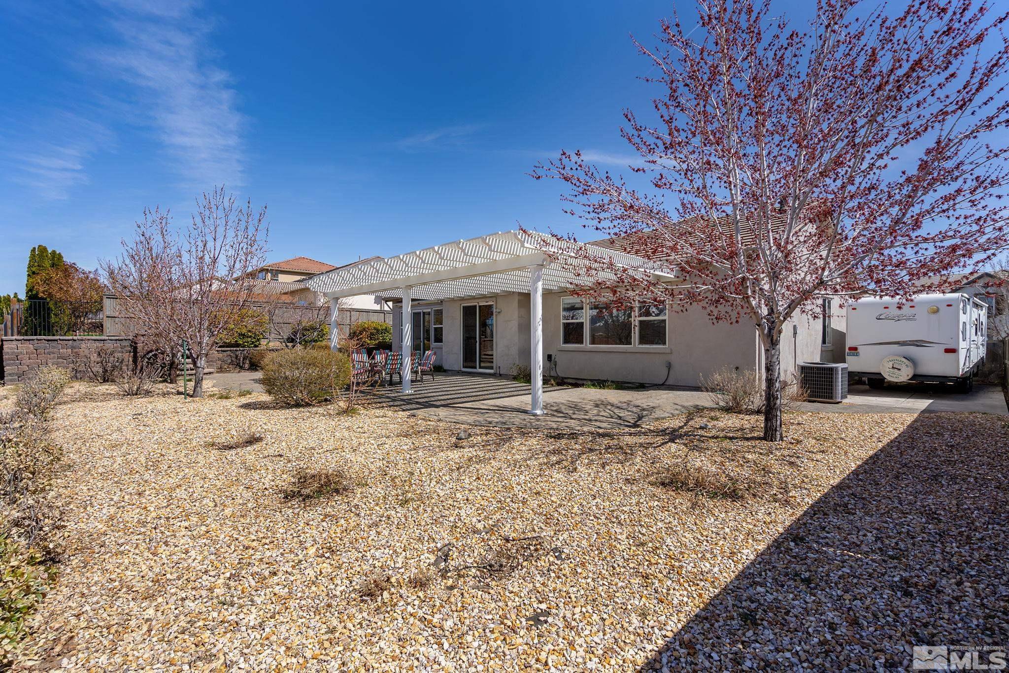 8115 Fire Opal Lane Reno, NV 89506 - Photo 31 of 40 a front view of a house with a dirt yard and a large tree