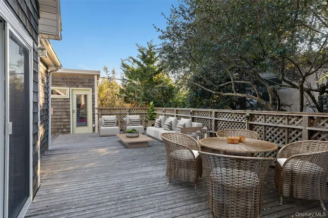 a view of a patio with couches table and chairs with wooden floor and fence